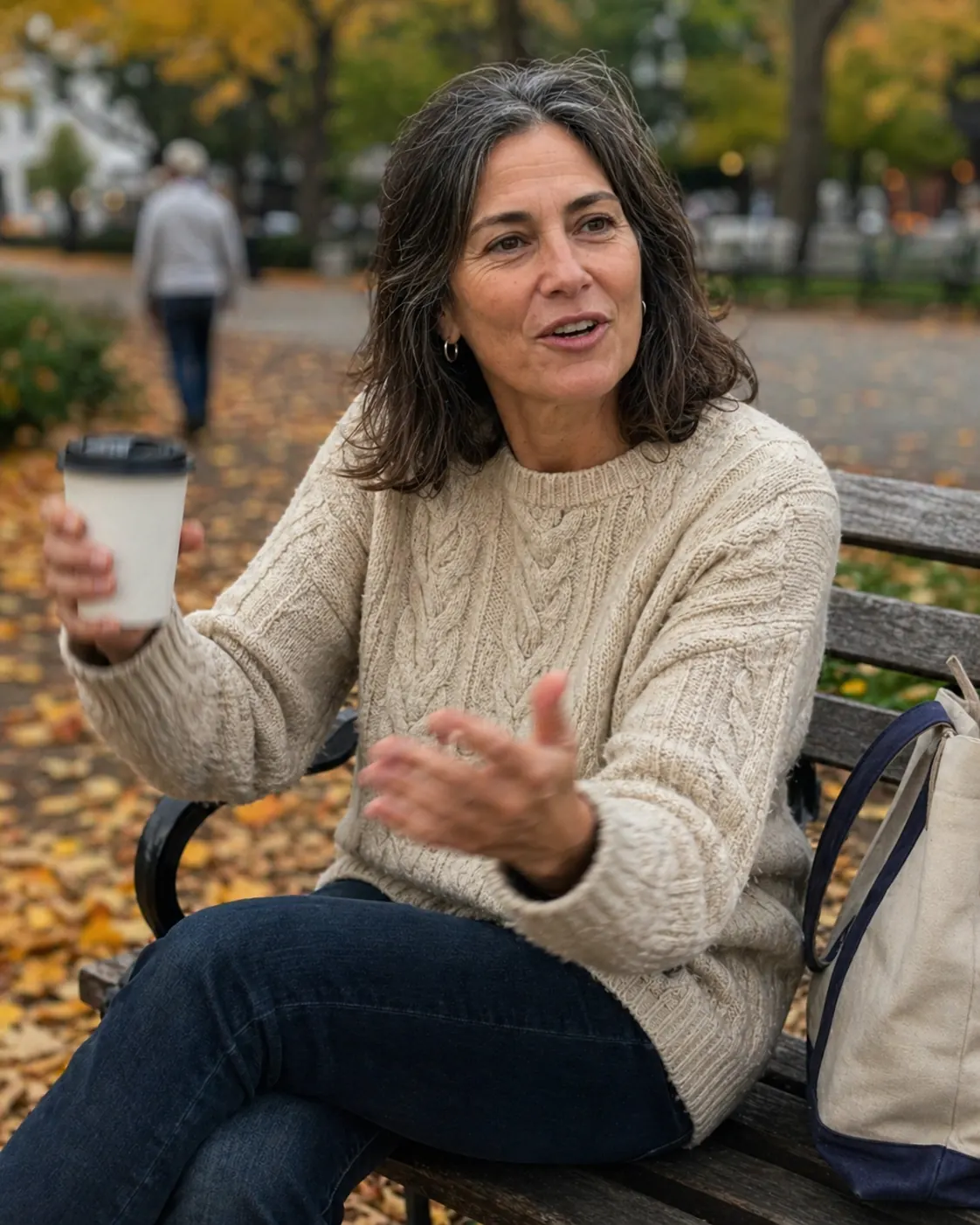 Jenna, 43, on a park bench with a coffee in autumn light